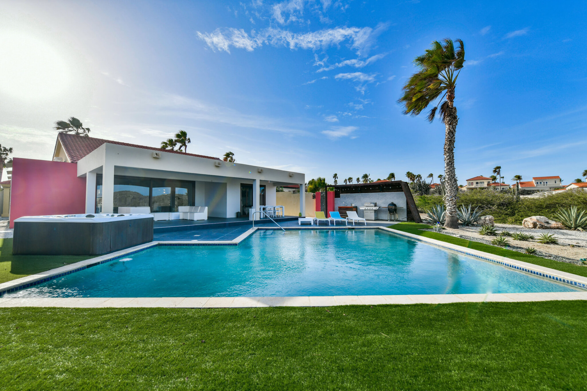 Modern Aruba villa with a large pool, lawn and palm tree